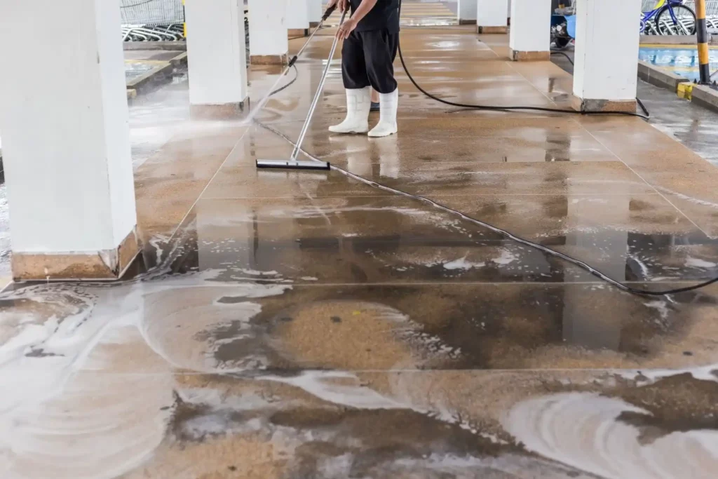 Serviços de limpeza industrial Profissional de uma empresa de limpeza industrial realizando lavagem de piso em ambiente fabril.