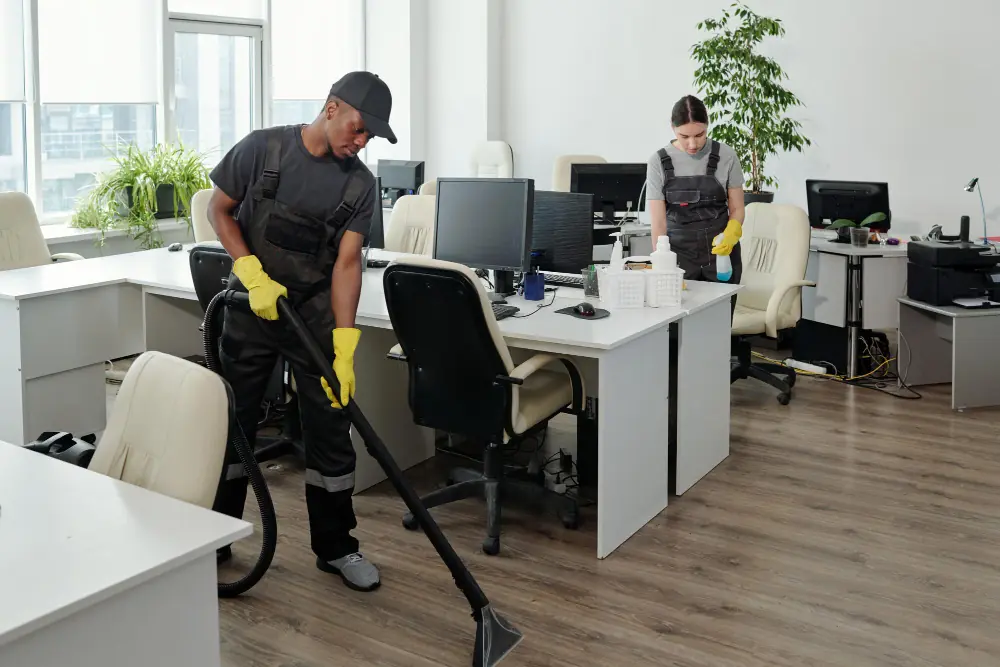 Equipe de limpeza empresarial higienizando escritório com aspirador e produtos de limpeza