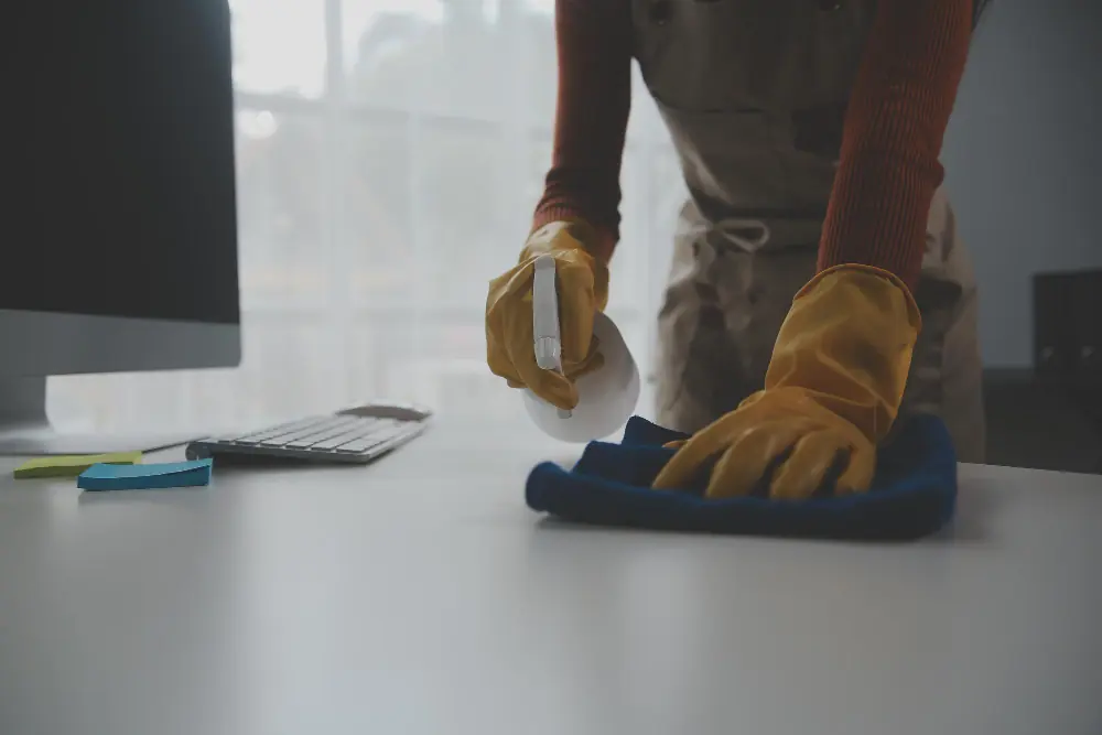 Profissional utilizando produtos de limpeza para empresas em mesa de escritório